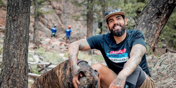 Photo of veteran with his dog in front of participants climbing