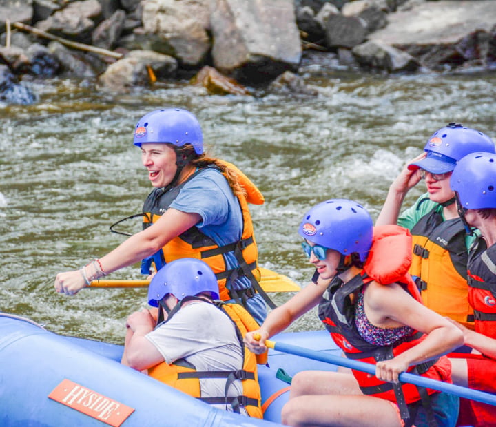 Close up of a group of 5 rafters excitedly going down a river.