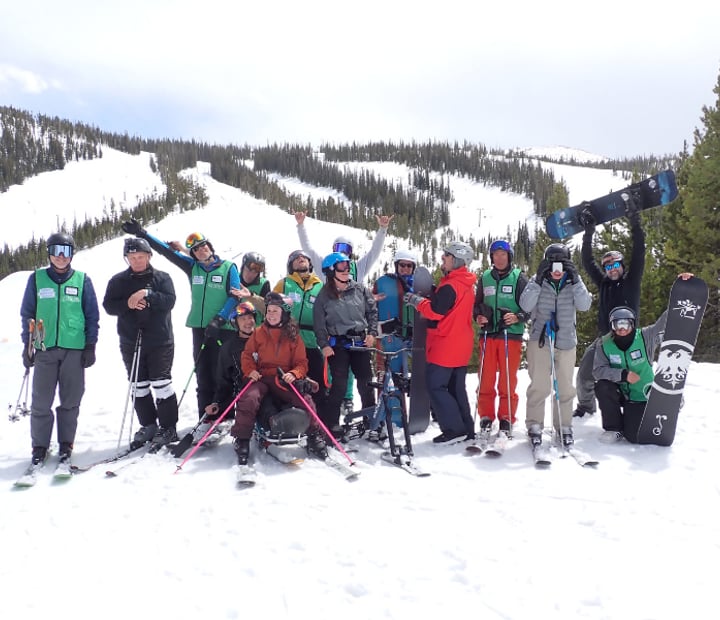 Military ski group posing silly at the base of mountain.