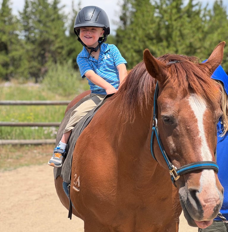 NSCD participant smiling riding on horse.