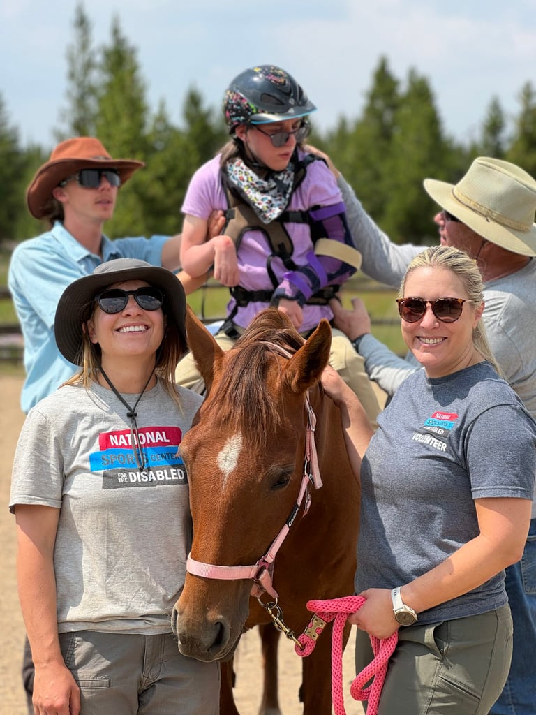 Participant receiving assistance during an adaptive horseback riding lesson with NSCD instructors and volunteers.