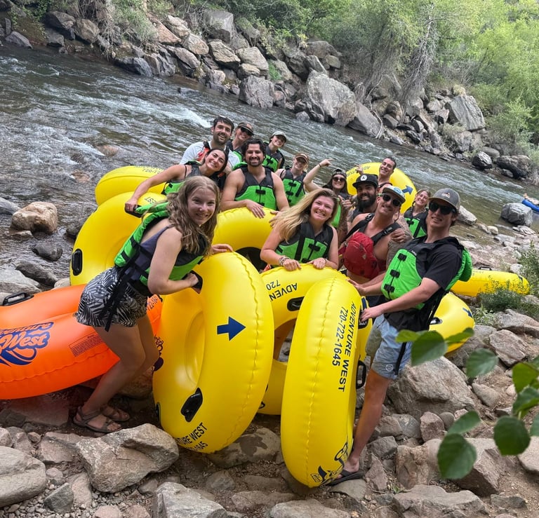 NSCD Staff are smiling together by a river before a staff appreciation tubing day on the water.