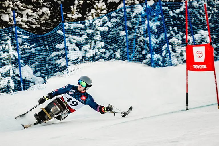 Skier with outriggers taking a quick turn on a snowy ski slope.