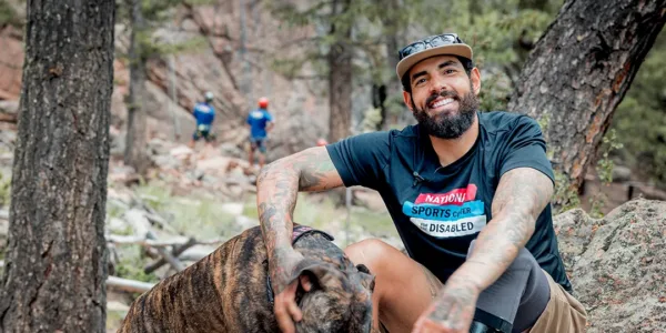 Photo of veteran with his dog in front of participants climbing