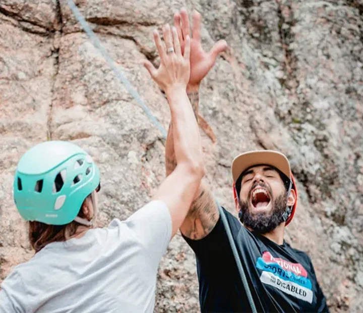 Participant and NSCD volunteer high-fiving and yelling in front of a rock face.