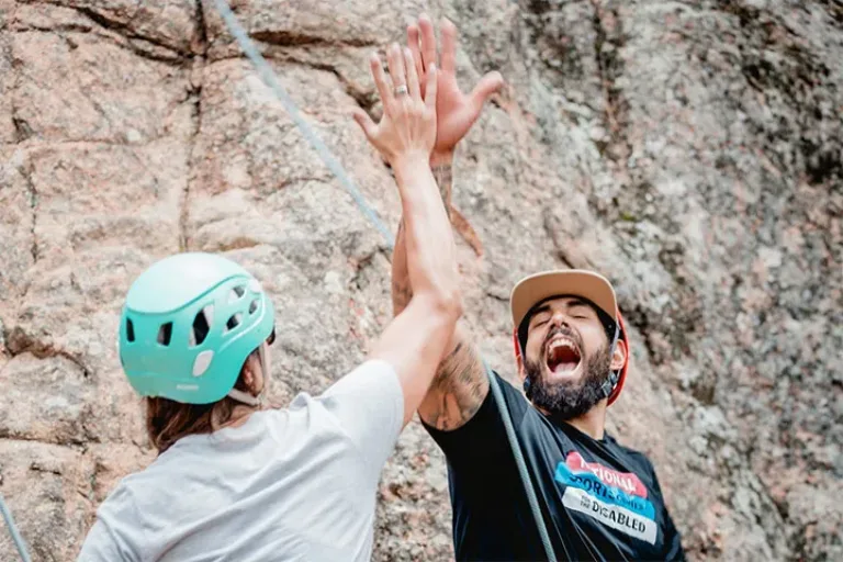Participant and NSCD volunteer high-fiving and yelling in front of a rock face.