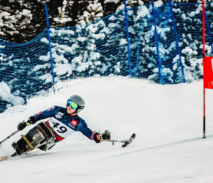 Skier with outriggers taking a quick turn on a snowy ski slope.