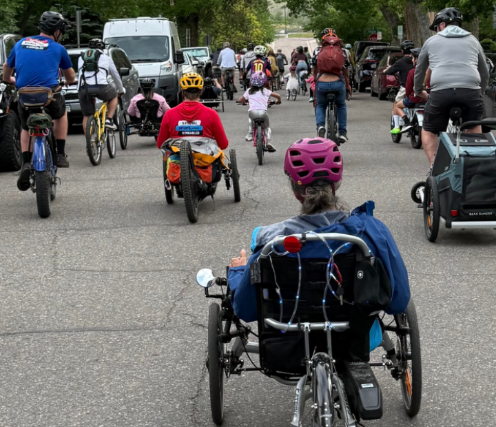 Group of adaptive riders riding down a street with other bicyclists during a community bike ride in Golden.