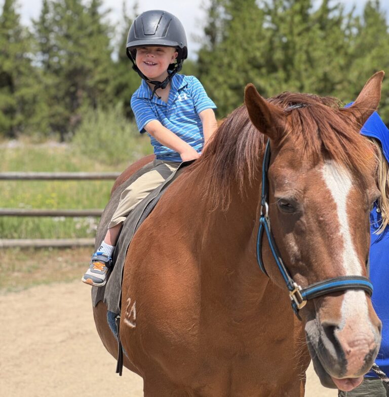 NSCD participant smiling riding on horse.