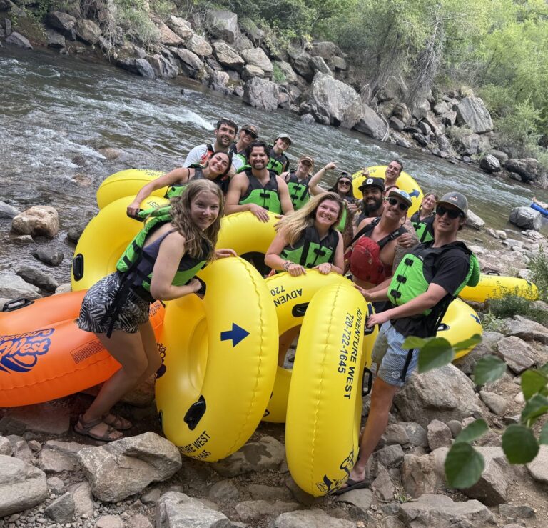 NSCD Staff are smiling together by a river before a staff appreciation tubing day on the water.