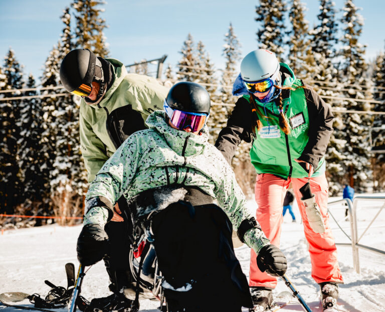 NSCD volunteer and instructor assist a participant during an adaptive ski lesson at Winter Park Resort.