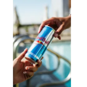 Red Bull can being passed from one hand to another.