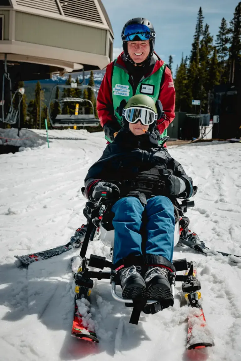 Photo of Volunteer with Adaptive Skier on Tetraski, both are smiling